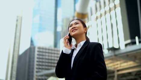 Hübsche-Geschäftsfrau-im-Gespräch-mit-Smartphone-bei-Outdoor-Büro