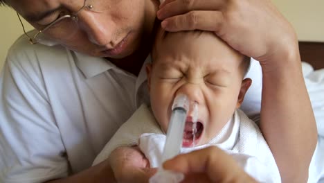 Asiatischen-Eltern-Spülung-Kleinkind-Baby-junge-Kind-Nase-mit-Spritze-für-Nasenspülung