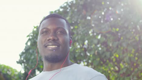 Afrikanische-Sportler-mit-Kopfhörern-lächelnd-in-die-Kamera-im-freien