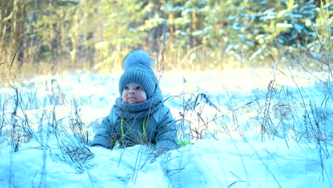 Glückliches-Baby-liegend-in-einer-Schneewehe.-Kind-erhebt-sich-aus-einer-Schneewehe.-Baby-aussehen-und-Lächeln