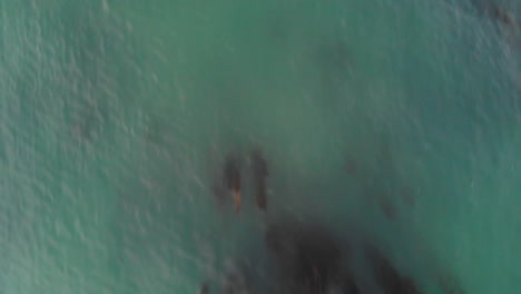 Camera-flying-over-the-ocean-water-to-beach-cliffs-at-sunset-time