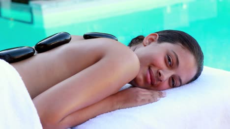 Peaceful-brunette-getting-hot-stone-massage-poolside