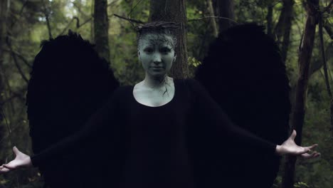 4k-Halloween-Dark-Angel-Frau-mit-schwarzen-Flügeln-im-Wald-Hände-aufstehen