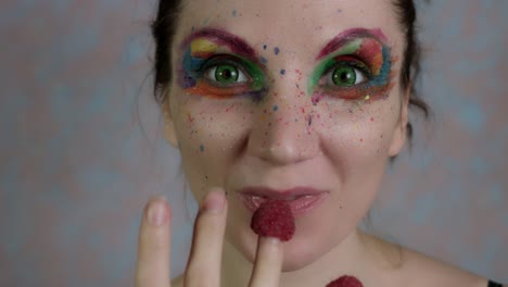 4-tiro-de-k-de-una-mujer-con-maquillaje-multicolor-comer-frambuesa