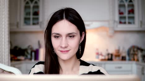 portrait-of-a-beautiful-young-brunette-woman-uses-laptop-in-a-bright-dining