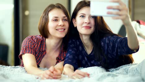 Zwei-glückliche-Frauen-Freunde-im-Bett-liegen-und-wodurch-Selfie-Morgen-und-viel-Spaß-im-Bett