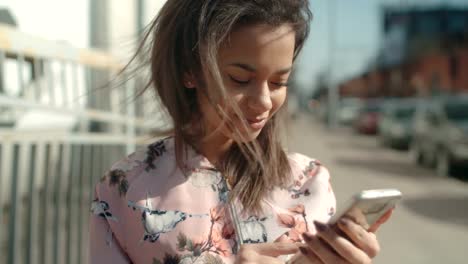 Portrait-of-young-African-American-woman-using-phone,-outdoors.