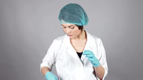 Young-female-doctor-in-gloves-holding-a-syringe-and-preparing-injection-isolated-on-grey-background.-Healthcare-concept.-Shot-in-4k