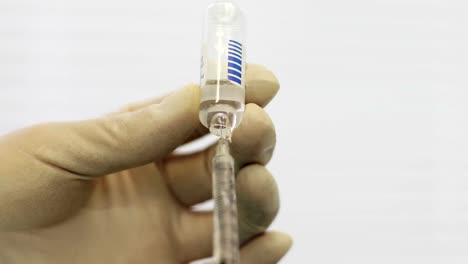 4K-Close-up-of-doctor's-hands-in-gloves-filling-syringe-with-injection-liquid.