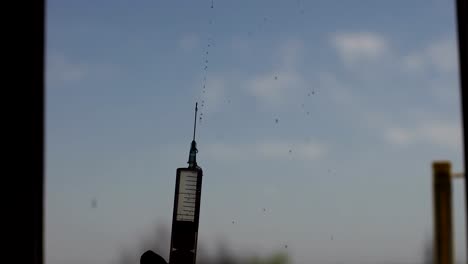 Close-up-of-a-silhouette-of-a-syringe-with-drops.