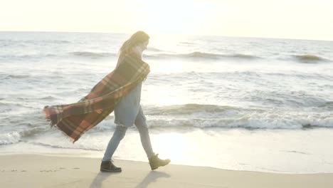 Junge-Frau-zu-Fuß-am-Ufer-des-Meeres.-Nachdenkliche-Frau-mit-Plaid-Zeit-allein-in-windigen-kalten-Tag-am-Strand-verbringen