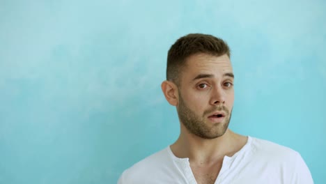 Portrait-of-young-man-actively-surprising-and-wondering-looking-into-camera-on-blue-background