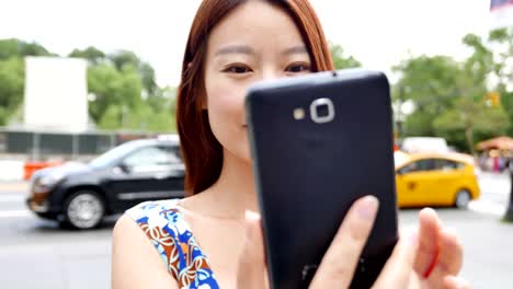 Hermosa-mujer-China-enviar-mensajes-de-texto-y-hablando-con-el-teléfono-en-la-ciudad.-Ser-feliz,-sonreír-y-divertirse.