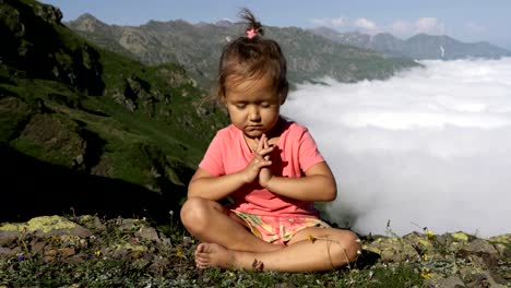 Little-cute-girl-meditating-on-top-of-mountain