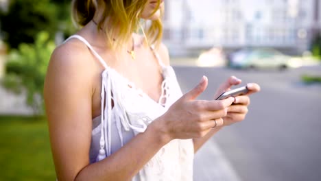 close-up-shot-of-a-woman's-hands,-who-holds-a-smartphone,-the-lady-looks-at-the-social-networks-of-her-friends,-she-is-on-the-street