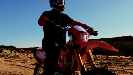 Imágenes-de-ángulo-bajo-del-piloto-de-Motocross-profesional-de-motos-FMX-está-parado-en-medio-de-la-cantera-y-terreno-Off-Road-extrema-con-vistas-a-lo-va-a-montar-hoy.