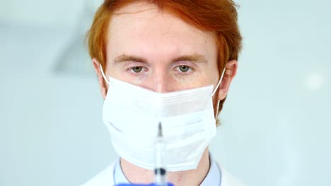 Close-Up-of-Redhead-Doctor-in-Mask-Holding-Injection,-Ready-to-inject