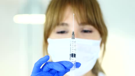 Close-Up-of-Female-Doctor-in-Mask-Holding-Injection,-Ready-to-inject