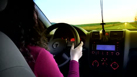 woman-driver-driving-a-car-toward-sunset,-pov