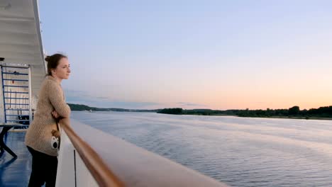 Frau,-die-Landschaft-vom-Deck-des-Kreuzfahrtschiffes-nach-Sonnenuntergang-bewundern