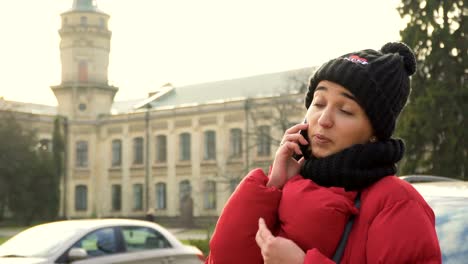 Junge-hübsche-Studentin-hat-Gespräch-am-Telefon-im-freien