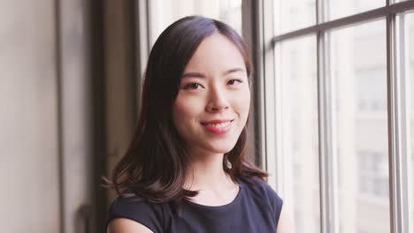 Chinese-businesswoman-turns-and-smiles-to-camera,-close-up