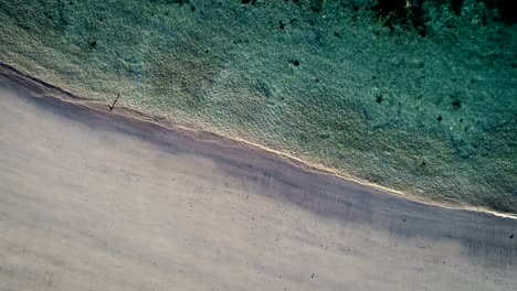 Aerial-view-waves-break-on-white-sand-beach.