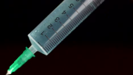 Hand-holding-a-syringe,-the-syringe-is-filled-with-clear-liquid-is-isolated-on-black-background.-Hypodermic-syringe-that-is-being-filled-with-vaccine