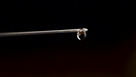 Medical-injection-syringe-with-drop-falling-from-the-needle-shallow-depth-of-field.-Drop-falling-from-needle.-Close-up-of-Hypodermic-syringe-falling-drop,-macro