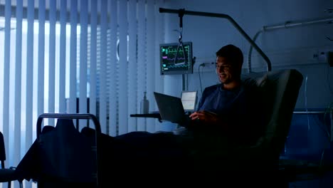 En-el-Hospital,-recuperación-de-hombre-paciente-utiliza-Laptop-mientras-la-mentira-en-la-cama.-Usando-la-tecnología-para-comunicarse-con-los-seres-queridos.