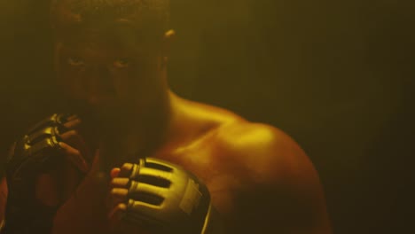 Close-up-shot-of-a-muscular-black-man-shadow-boxing-and-posing-on-a-foggy-dark-background