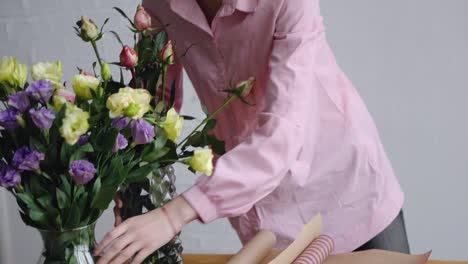 The-girl-rearranges-the-vase-of-flowers-and-prepares-the-kraft-packaging-paper-for-the-bouquet