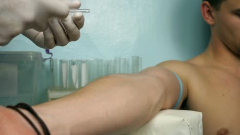 Male-hand-of-doctor-injects-a-syringe-into-a-vein-of-patient.-Arm-of-medic-making-injection-vaccine-to-ill-man-at-hospital.-Close-up-Side-view