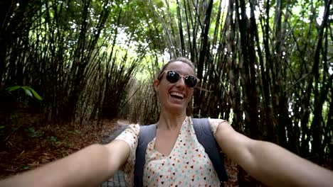 Joven-toma-un-retrato-selfie-en-bosque-de-bambú-en-Bali,-Indonesia.-Gente-de-viaje-divertido-compartir-concepto-de-medios-de-comunicación-social-de-la-tecnología.-4K