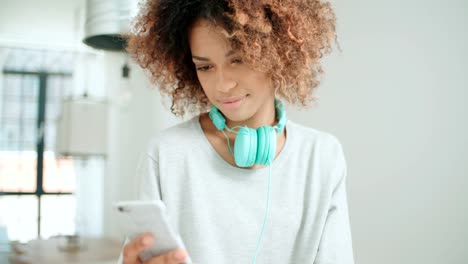 Beautiful-young-afro-american-woman-texting-on-mobile-phone-at-home.