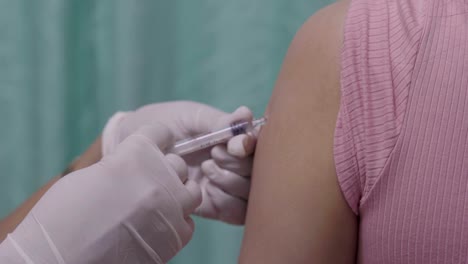 Doctor-holding-syringe-for-vaccination-to-upper-arm-of-patient