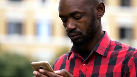 hombre-africano-negro-atractivo-escribir-en-su-teléfono-inteligente-en-la-calle