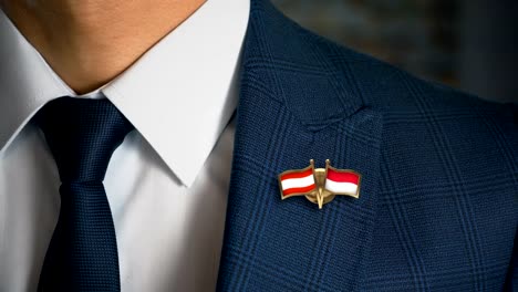 Businessman-Walking-Towards-Camera-With-Friend-Country-Flags-Pin-Austria---Indonesia