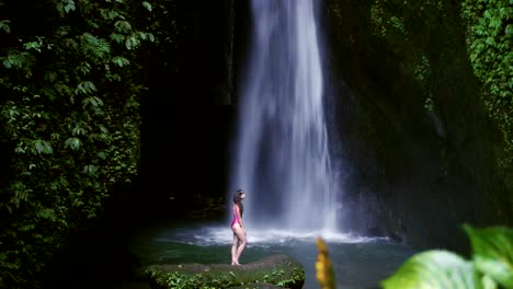 Frau-im-Badeanzug-entspannend-am-Wasserfall-in-Bali,-Indonesien.-Tropischer-Wald-und-Wasserfall