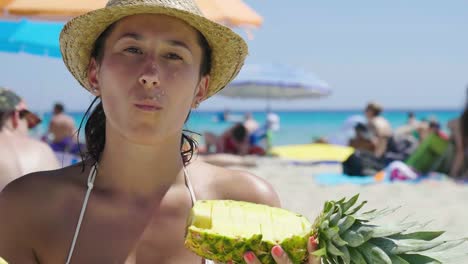 Porträt-eines-schönen-jungen-Mädchens-am-Meer,-eine-Ananas-in-einem-Badeanzug-in-einem-Strohhut-Strand-Hintergrund-halten.