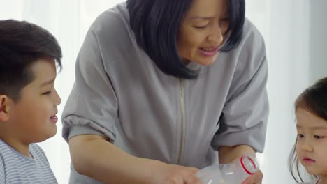 Asian-Mother-Pouring-Milk-to-Kids-during-Breakfast