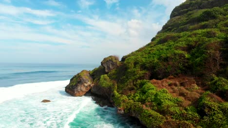 Vista-aérea-de-las-rocas-y-el-azul-océano-con-olas-en-la-isla