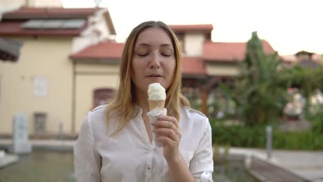 Portrait-of-beautiful-positive-young-woman-eating-ice-cream-on-background-of-palm-trees