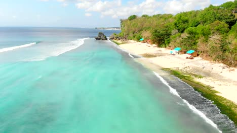 Tropical-beach-and-turquoise-ocean-with-waves-in-Bali,-aerial-video.