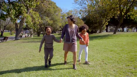 Happy-Asian-mother-holding-hands-with-African-American-kids