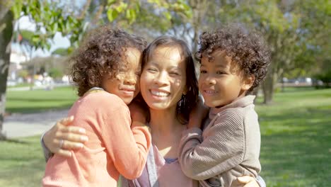 Happy-African-American-kids-kissing-and-hugging-Asian-mother