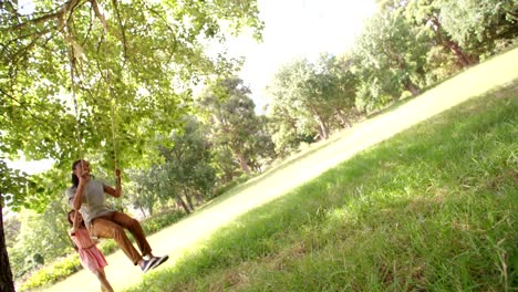 Cute-daughter-pushing-her-dad-on-a-swing