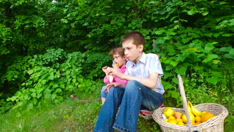 Kinder-essen-Obst-im-Wald.-Mädchen-isst-apricot.-Junge-Essen-eine-Banane,-Aprikose.