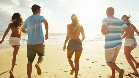 Gruppe-von-Freunden-Spaß-einem-Strandspaziergang-bei-Sonnenuntergang