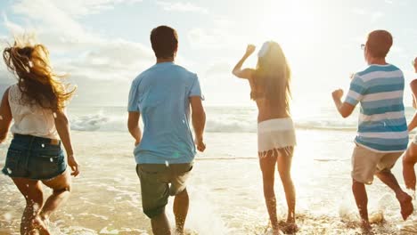 Gruppe-von-Freunden-Spaß-einem-Strandspaziergang-bei-Sonnenuntergang